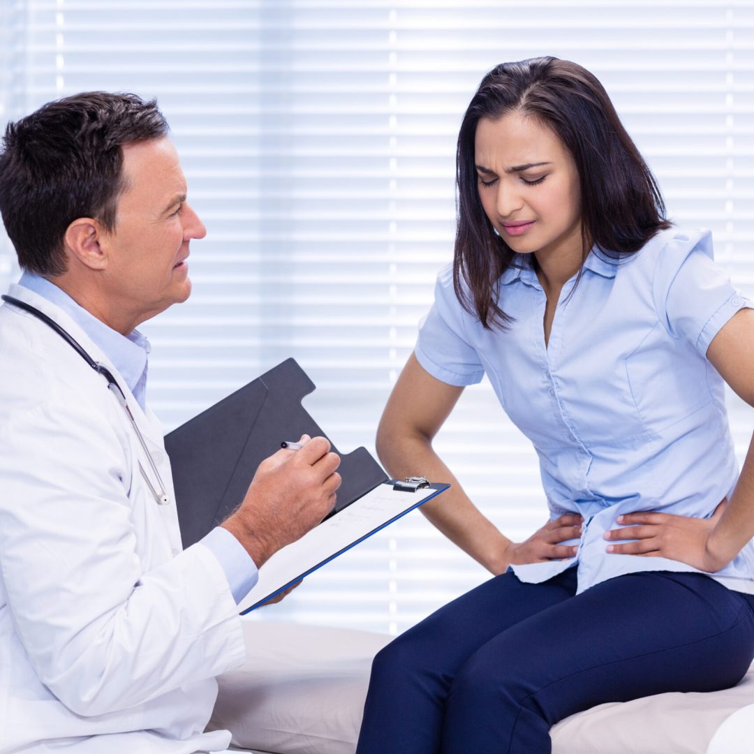 Patient suffering from stomach ache while consulting doctor in clinic